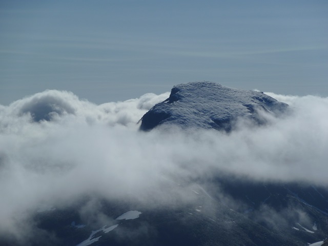 Toppen av Rondeslottet med nysnø stikker opp i morgentåken. Her sett fra vest.